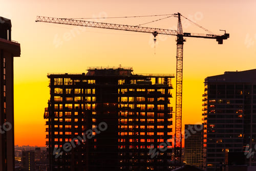Preview: Silhouette of Crane and Building Under Construction at Dusk.