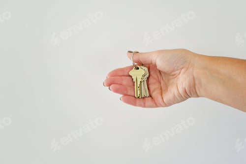 Preview: Female hand holding a set of keys, minimal - new home or office, real estate, investment opportunity