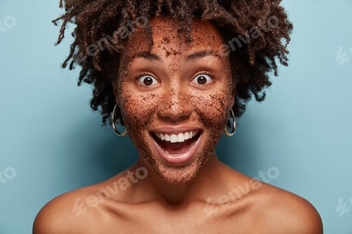 Preview: Close up of happy black woman has scrub mask, smiles broadly, has face treatments, smiles broadly, s