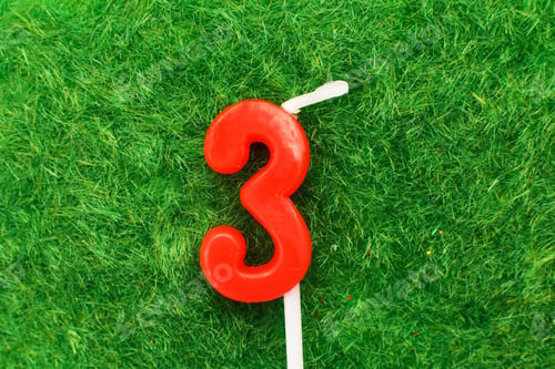 Preview: candle in the form of number 3 on the green grass background, a place for a greeting text