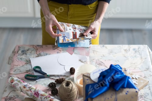 Preview: High angle view of mid adult woman wrapping gift at table