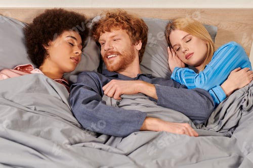 Preview: non traditional relationship, polygamy, three adults, happy redhead man waking up near multicultural