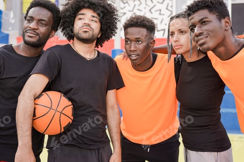 Preview: Group of multiracial friends hugging each other in the city while holding basketball