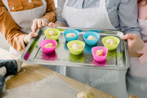Preview: Dough divided into silicone colourful cups lying on metal baking tray.