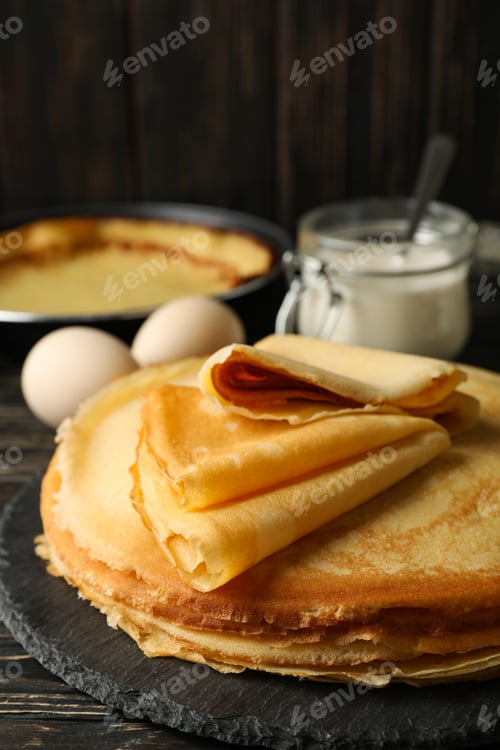 Preview: Concept of tasty breakfast with thin pancakes on wooden table