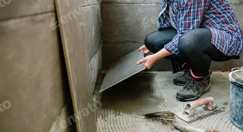 Preview: Female builder laying a new tile floor