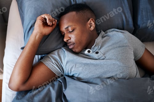 Preview: Cropped shot of a handsome young man sleeping in his bed during a day off at home alone