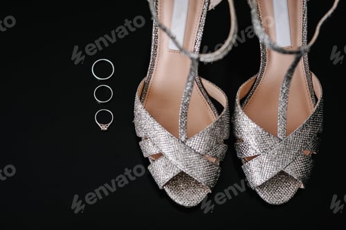 Preview: Silver shoes and rings, composition isolated on the black background. Accessory bride. Footwear.