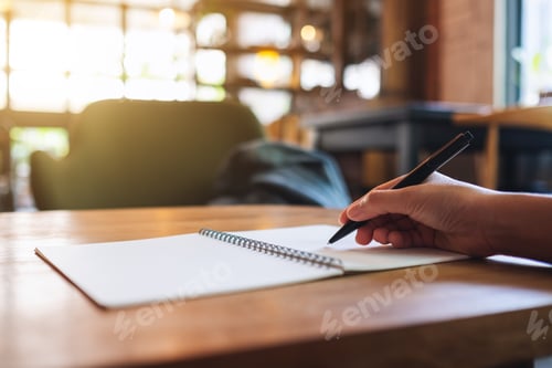 Preview: Closeup image of a woman writing on a blank notebook on the table