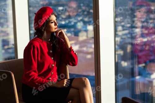 Preview: Woman wearing red fashion including beret and sweater looking out a window at a beautiful view