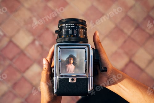Preview: Looking down on an old camera, taking a photo of a young afro girl