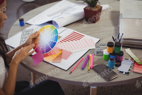 Preview: Businesswoman holding colour swatch at office desk