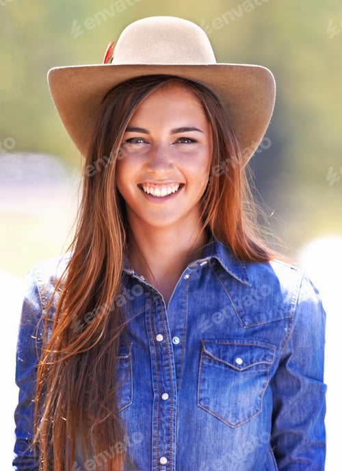 Preview: Owning the cowgirl look. An attractive young cowgirl standing in the stables.
