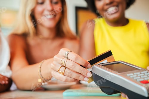 Preview: Close up portrait of a smiling woman making a payment with her credit card at a card reader