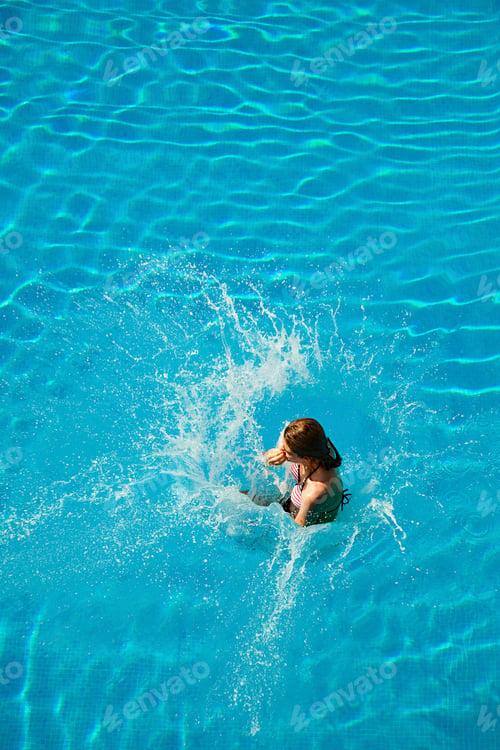 Preview: Young woman jumping into swimming pool