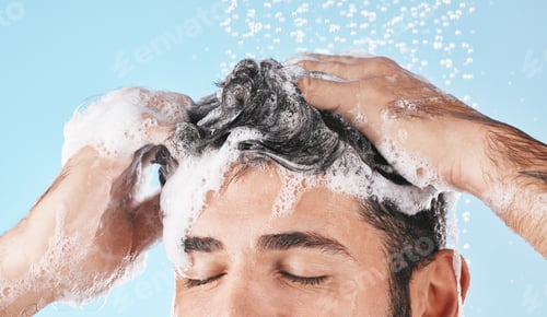 Preview: Face, water splash and shampoo shower of man in studio isolated on a blue background. Water drops,