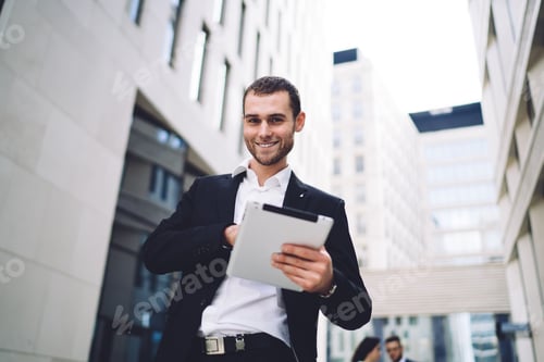 Preview: Cheerful man using tablet on street