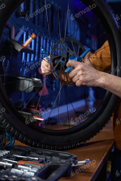 Preview: Mechanic adjusting and fixing bike brake disk with wrench at self-repair shop