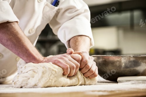 Preview: A chef's hands kneading bread dough on a floured worktop.