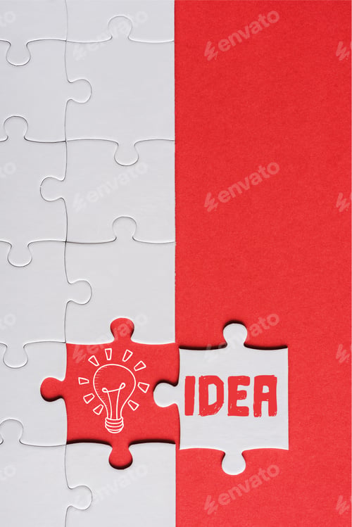 Preview: top view of incomplete jigsaw near white puzzle piece with idea lettering isolated on red