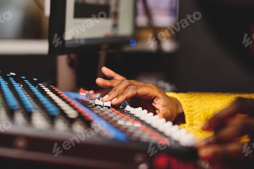 Preview: Crop ethnic female radio host using mixing console in studio