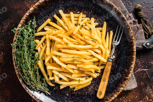 Preview: Homemade Baked Potato french fries in rustic palte with thyme. Dark background. Top view