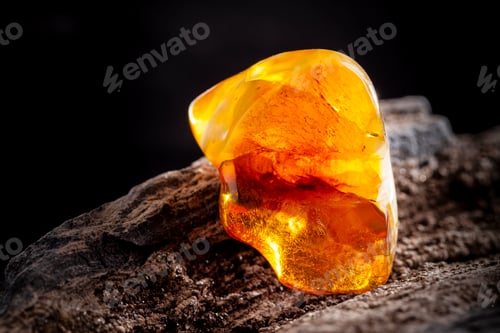 Preview: Natural amber. A piece of yellow opaque natural amber on large piece of dark stoned wood