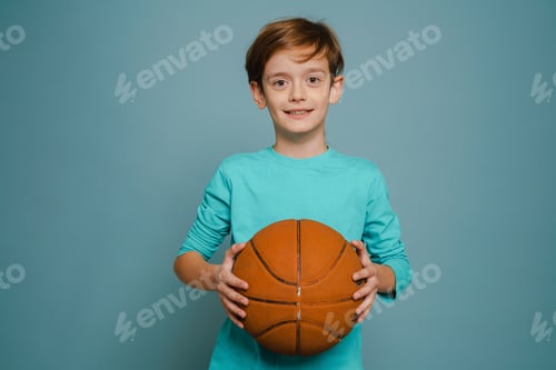 Preview: Ginger white boy smiling while posing with basketball
