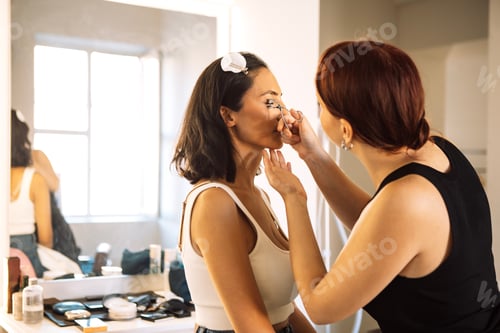 Preview: Asian woman receiving professional makeup application from stylist