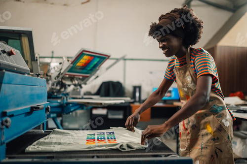Preview: Happy interracial print shop worker putting product into a dryer.