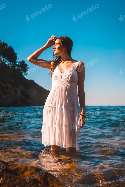 Preview: A young caucasian brunette in a white dress bathing in the sea water, summer lifestyle