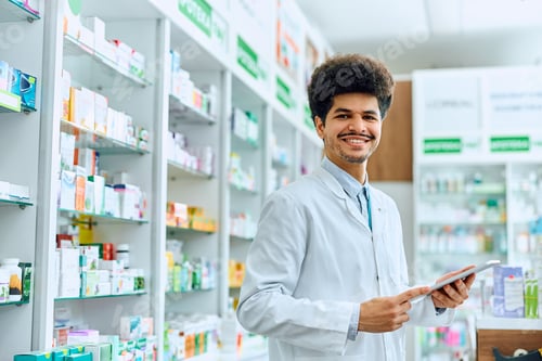 Preview: Happy Middle Eastern pharmacist working in drugstore and looking at camera.