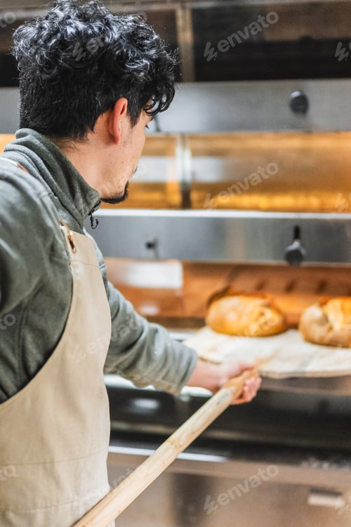 Preview: Baker taking freshly baked bread out of oven with peel