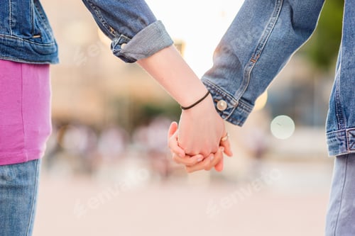 Preview: Unrecognizable lesbian couple holding hands. Young dating together in a female relationship