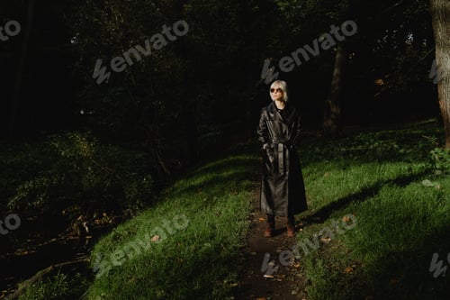 Preview: a woman in full growth stands in the forest looking to the side