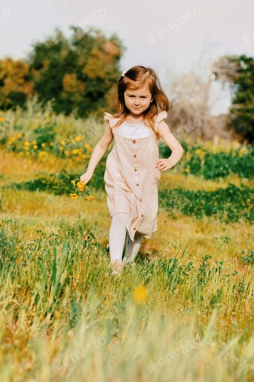 Preview: Toddler girl wear casual cotton dress running in field with yellow flowers ,enjoying sunny day