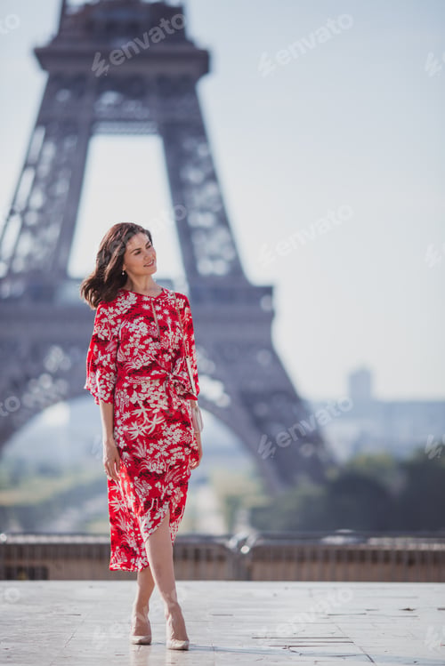 Preview: Woman with black hair in red dress is standing with the Eiffel tower on the background in Paris