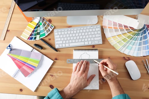 Preview: Man drawing in sketchbook with pencil and ruler at wooden table, top view