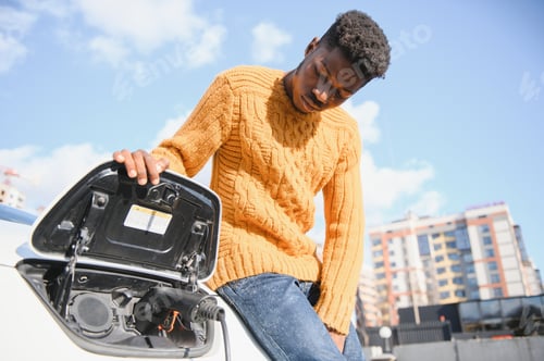 Preview: African American man charging his electric car.