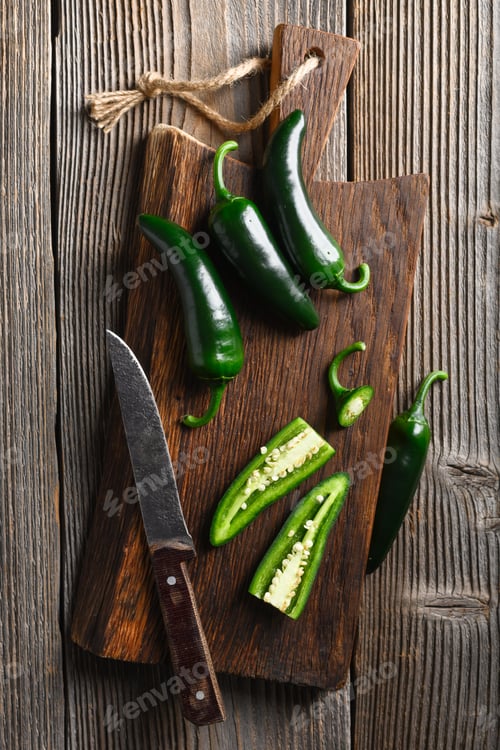 Preview: Black jalapeno with knife on rustic wooden cutting board