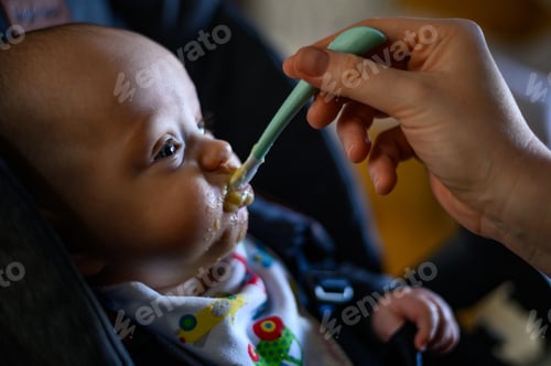 Preview: Adorable cute baby eating baby food while mom feeds him