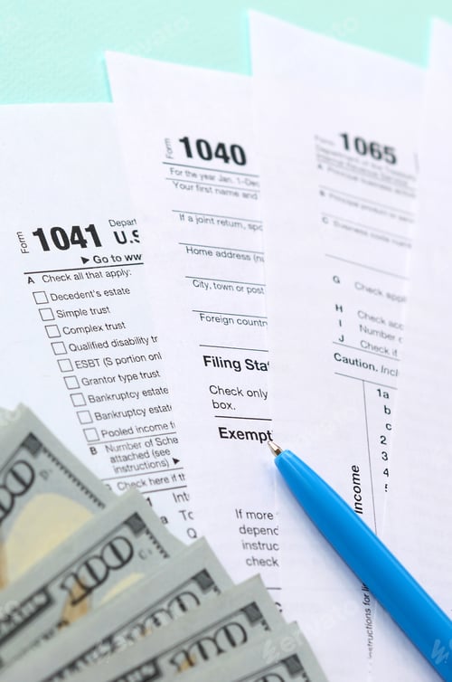 Preview: Tax forms lies near hundred dollar bills and blue pen on a light blue background. Income tax return.