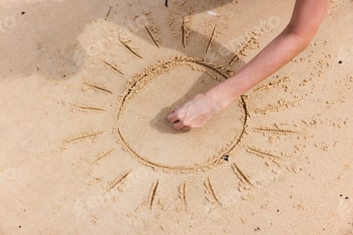 Preview: Person drawing a circle in the sand with the sun in the center on a beach