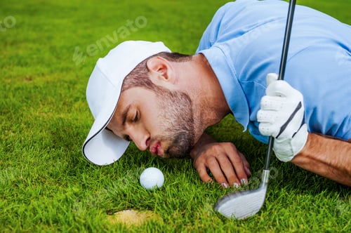 Preview: Golf cheats. Close-up of young golfer blowing at the ball while lying near the hole