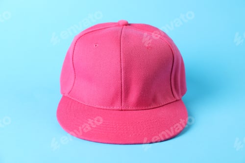 Preview: One pink baseball cap on light blue background, closeup. Mockup for design