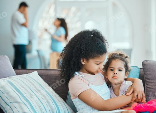 Two Little Girls Embracing on Sofa at Home