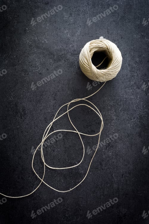 Preview: Ball of twine unrolling on dark stone surface