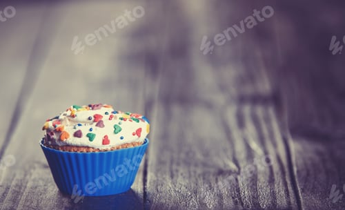 Preview: Brightly Decorated Cupcake with Heart Sprinkles on Table