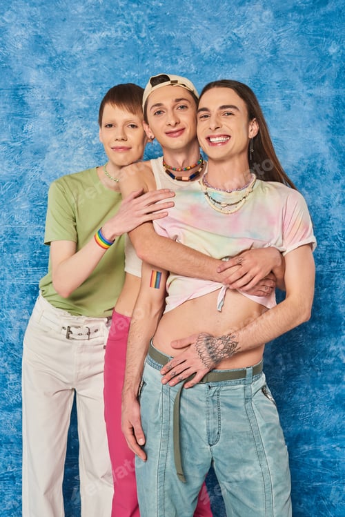 Preview: Cheerful homosexual community in stylish outfits hugging each other and looking at camera while
