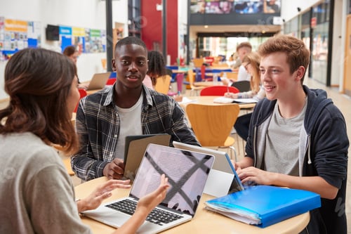 Preview: Teacher Talks To Students In Communal Area Of College Campus